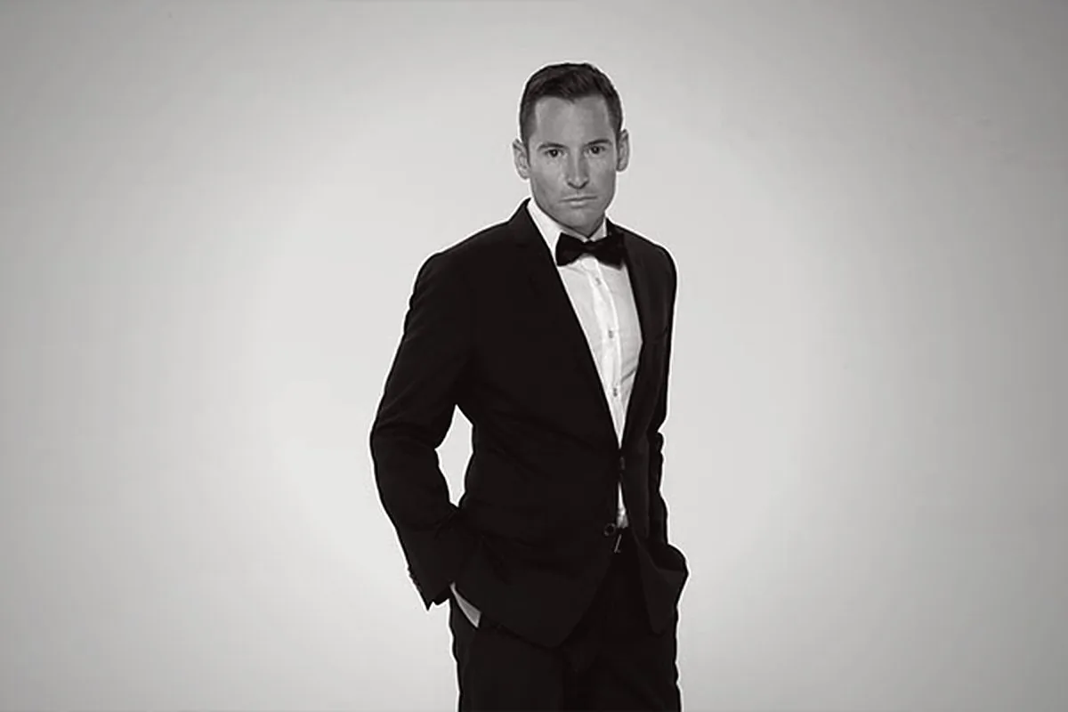 Studio portrait of Edward De Valle II in black tie, photographed against a pale ground