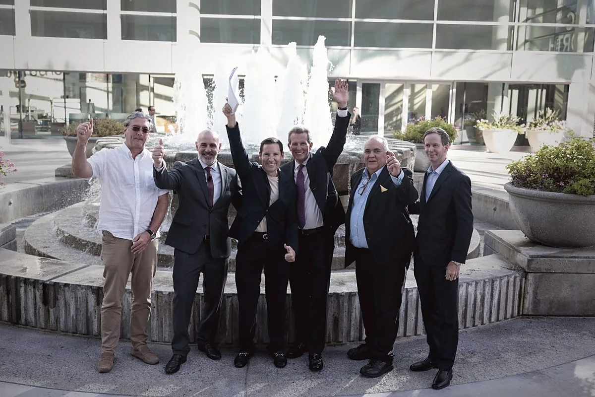 The Grupo De Valle team raising a toast beside a fountain after the signing